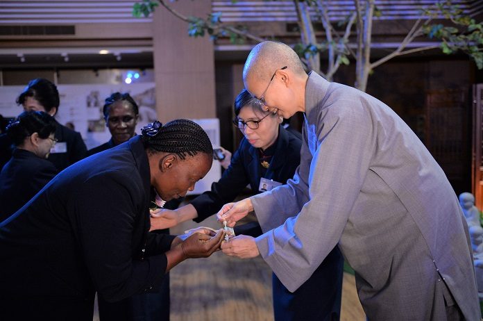 莫三比克慈濟志工瑪麗亞過去自怨自艾封閉自己，加入慈濟志工後獲得重生，圖為靜思精舍法師為瑪麗亞掛上佛珠。（圖為慈濟基金會提供）