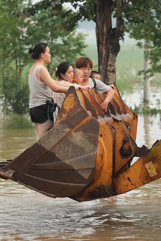 圖為8月2日涿州民眾，乘坐在鏟車上等待轉移。圖／中新社