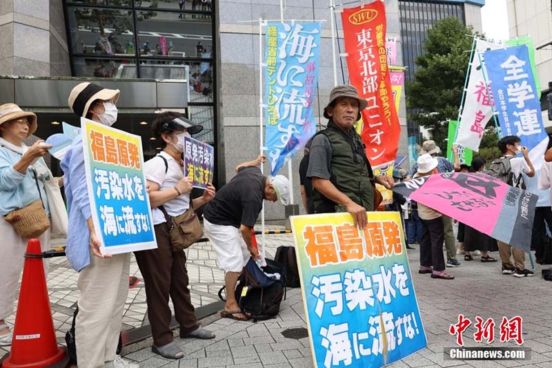日本排放核污水當天，日本民眾在東京電力公司總部附近舉標語抗議。圖／取自中新社