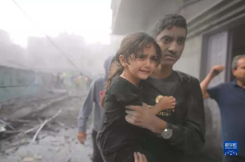 加薩南部城市拉法一名男子抱著小女孩走在遭以色列空襲的廢墟中。圖／取自新華社