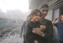 聯合國:以巴衝突11天 已有30萬童無家可歸 加薩南部城市拉法12日的空襲後,驚魂未定的小女孩被抱離廢墟。圖/取自新華社
